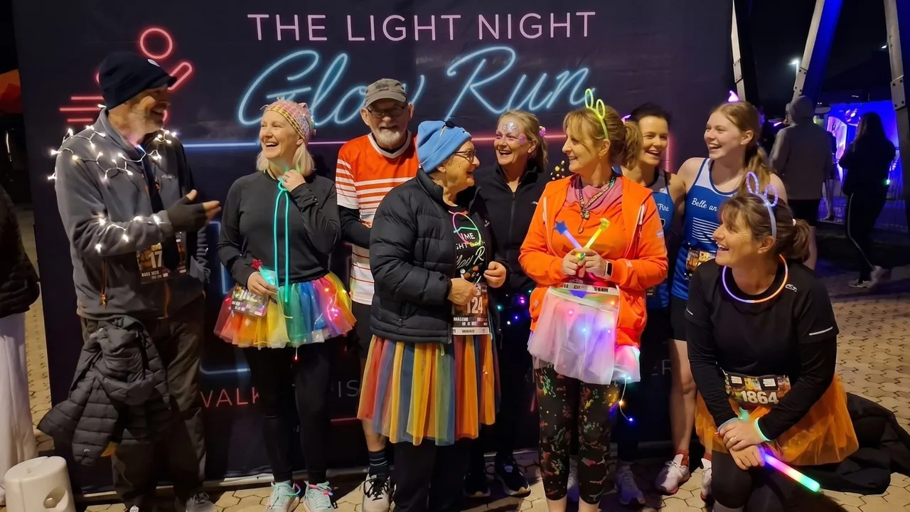 Runners in tutus and fairy lights laughing together at The Light Night Glow Run.