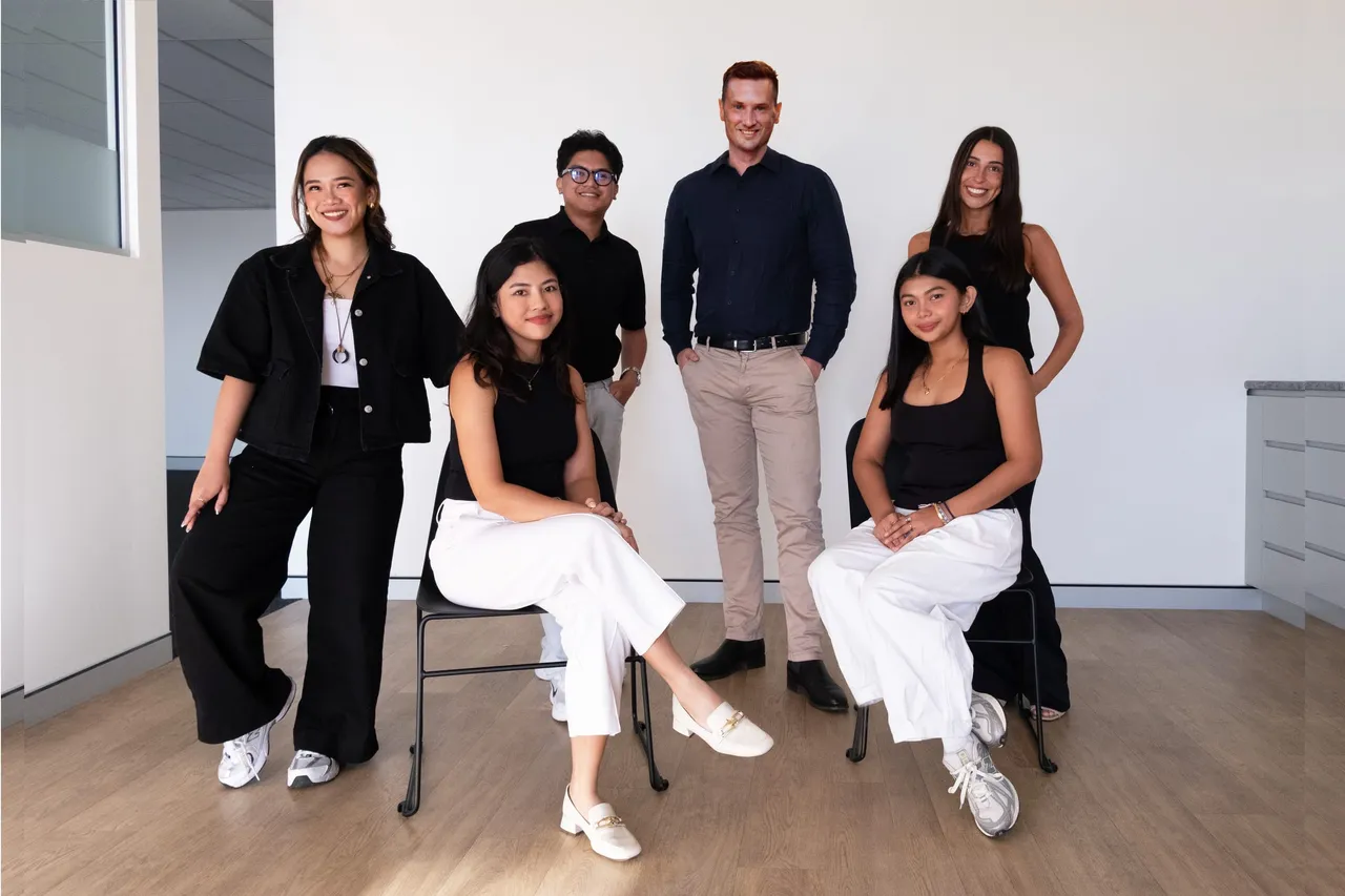 Six members of the MNO Ventures team in their office, four standing and two seated.